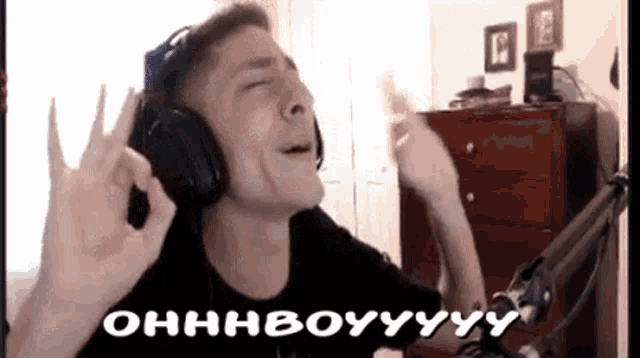 a man wearing headphones is singing into a microphone while making a ok sign .