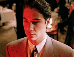 a man in a suit and tie is standing in a dark room .