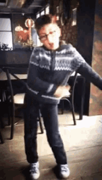 a young man in a sweater and jeans is dancing in a restaurant