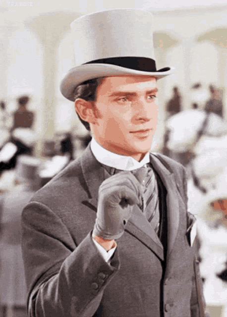 a man in a top hat and gloves is standing in a room