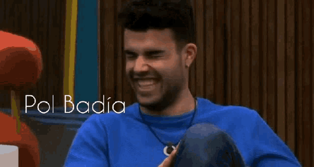 a man in a blue shirt is laughing with the words pol badia written above him