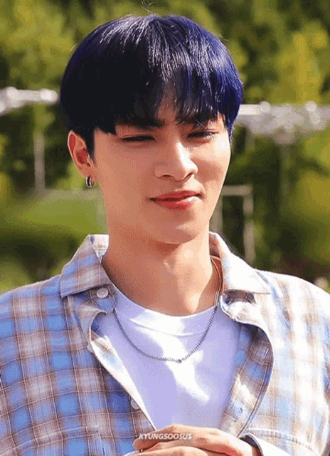 a young man with blue hair is wearing a plaid shirt and a white shirt