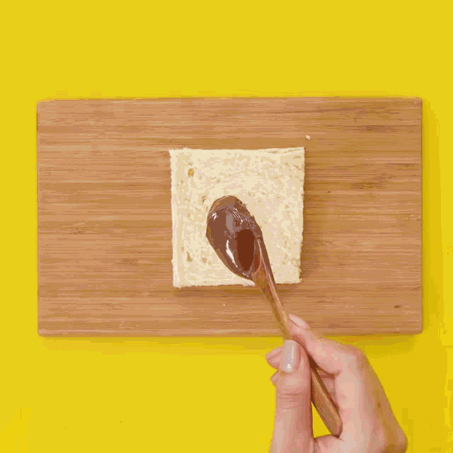 a person is spreading chocolate on a piece of bread