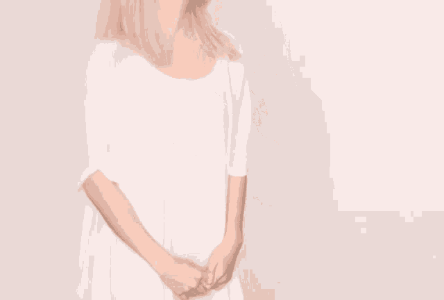 a woman in a white dress with her hands folded