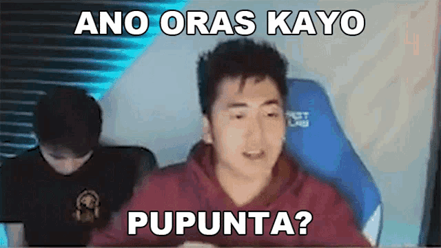 a man in a red hoodie is sitting in front of a computer screen with a caption that says ano oras kayo pupunta ?