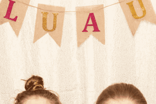 two girls are standing in front of a banner that says luau