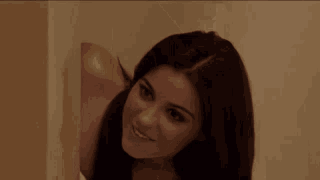 a woman with long dark hair is smiling and looking at the camera .