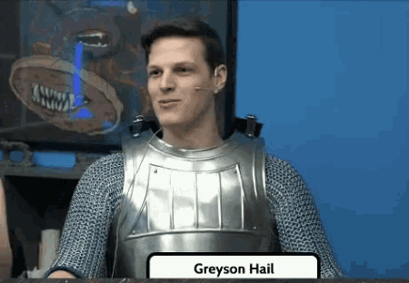a man in armor is sitting at a table with a sign that reads greyson hail