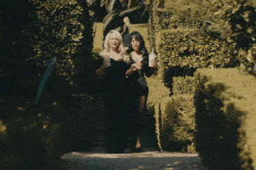 two women in black dresses are walking down a staircase