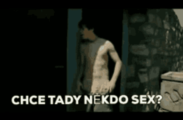 a shirtless man is standing in front of a door with the words chce tady nekdo sex written on the bottom .