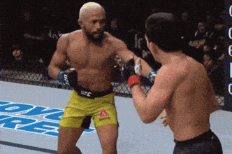 two men are fighting in a ring and one of them is wearing shorts that say ufc on them