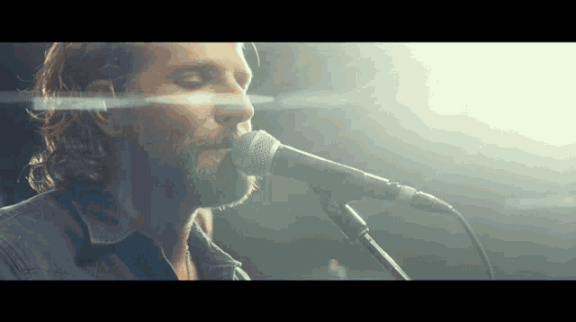 a man singing into a microphone with a light shining on his face