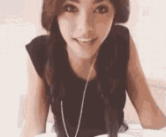a woman is sitting on a bed wearing headphones and smiling at the camera .