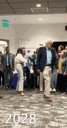 a man in a suit is walking down a hallway with 2028 written on the bottom