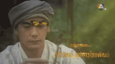 a man in a turban is holding a butterfly in front of his face .