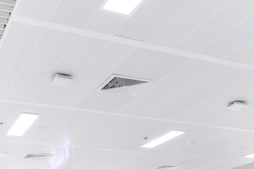 a white ceiling with a ventilation fan and a smoke detector