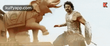 a man is standing next to a statue of an elephant and holding a shield .