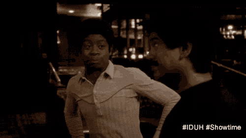 a man in a white shirt is talking to another man in a dark room with #iduh #showtime written on the bottom