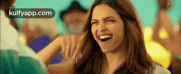 a woman is laughing while holding a man 's arm and smiling .