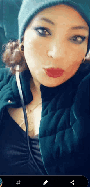 a woman wearing a green hat and a black jacket looks at the camera