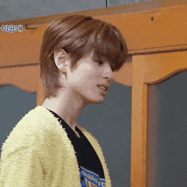 a close up of a person 's face with a yellow sweater and a t-shirt that says ' childhood '