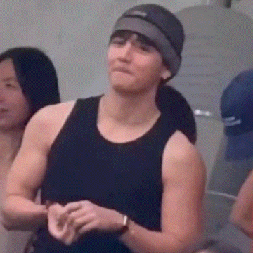 a man wearing a black tank top and a hat is standing in a room .