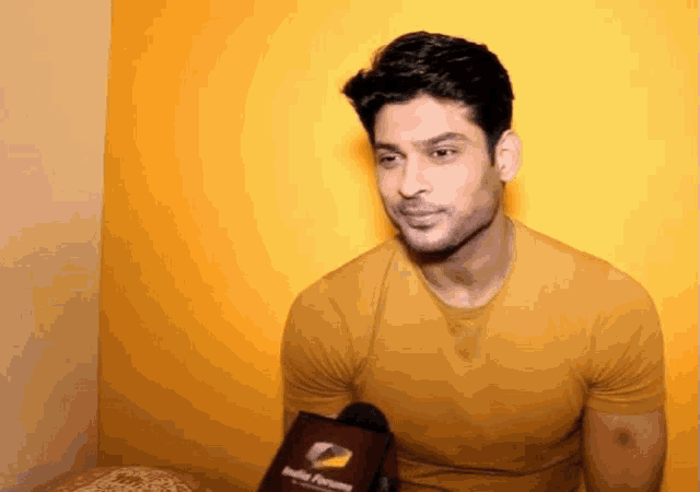 a man in a yellow shirt is talking into a microphone with india forum written on it