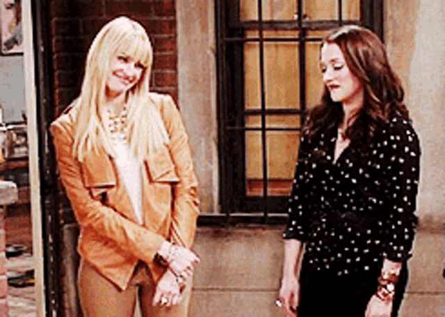 two women are standing next to each other in front of a window and smiling