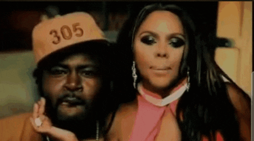 a man wearing a hat that says 305 is standing next to a woman in a pink dress
