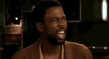 a man with a beard is making a funny face while wearing a brown jacket .