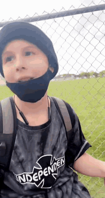 a young boy wearing a mask and a tie dye shirt is sitting on a bench .