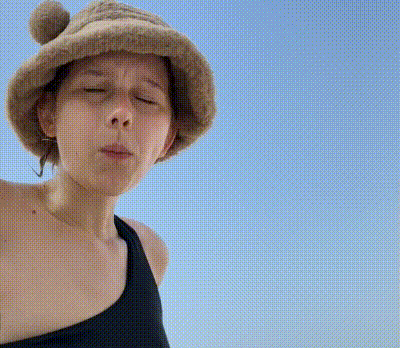a woman wearing a hat and a black tank top looks at the camera