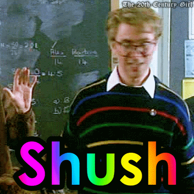 a man stands in front of a blackboard with the word shush in rainbow letters