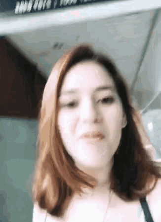 a woman with red hair is making a funny face while wearing a black bra .