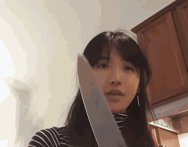 a woman is holding a large knife in her hand