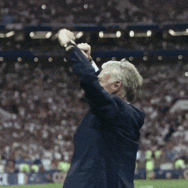 a man in a suit holds his arms in the air