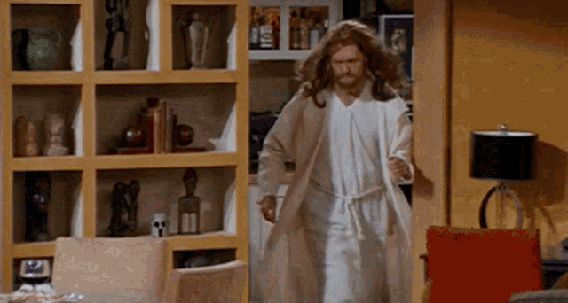 a man in a bathrobe is walking through a living room .