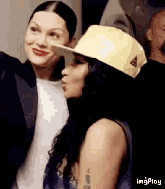 a woman wearing a yellow hat is kissing another woman .