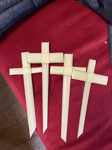three crosses made out of palm leaves are sitting on a red cloth