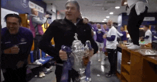 a man is holding a trophy in a locker room surrounded by people