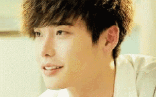 a close up of a young man 's face with a white shirt on and a smile on his face .