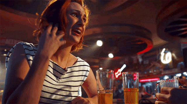 a woman is talking on a cell phone while sitting at a bar