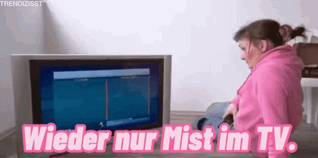 a woman is sitting in front of a tv with the words wieder nur mist im tv written in pink