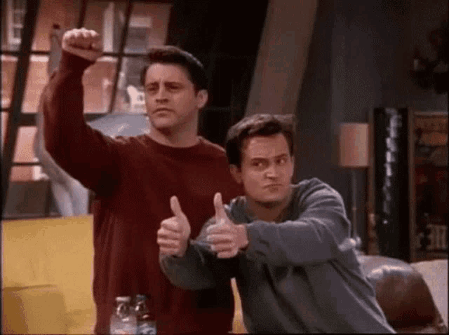 two men are giving each other a thumbs up sign
