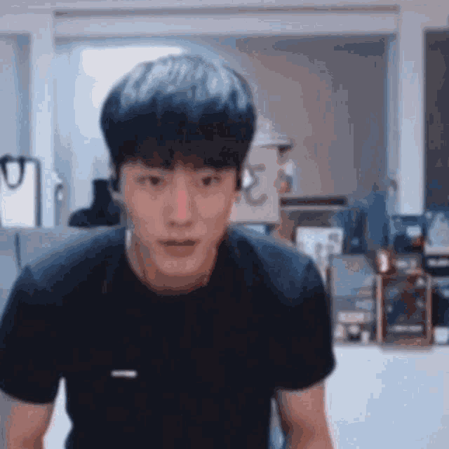 a young man wearing headphones and a black t-shirt is looking at the camera .