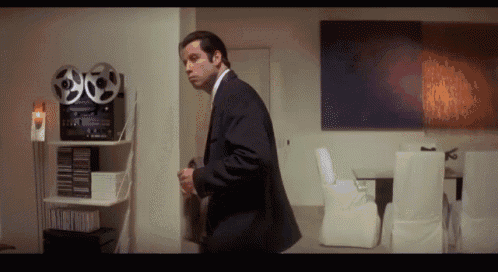 a man in a suit is standing in front of a reel to reel recorder