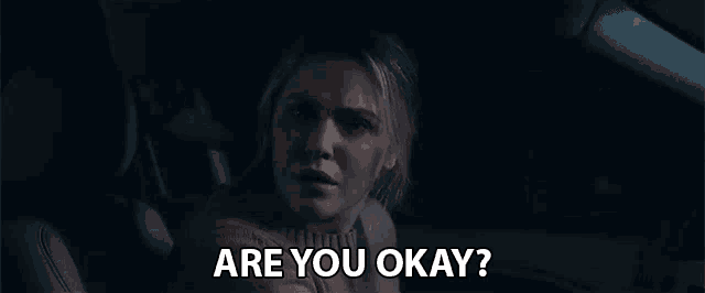a woman is sitting in a car with the words `` are you okay '' written on the screen .