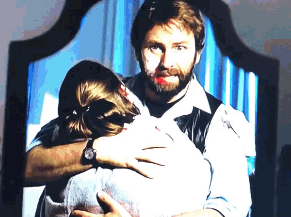 a man with a beard is hugging a woman with blood on her face