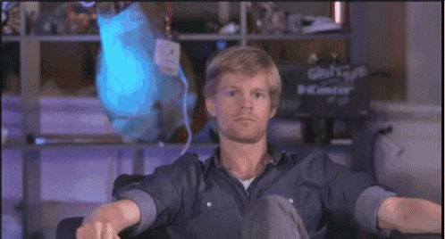 a man in a blue shirt is sitting in front of a sign that says ' ghost ' on it