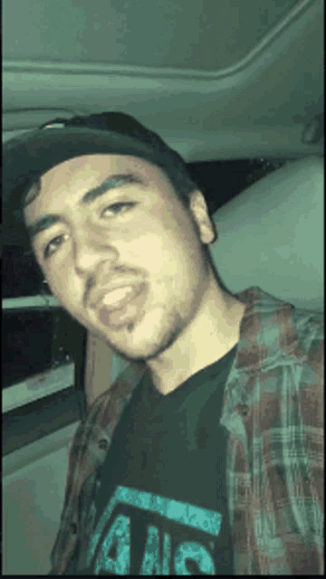 a man wearing a plaid shirt and a black vans shirt